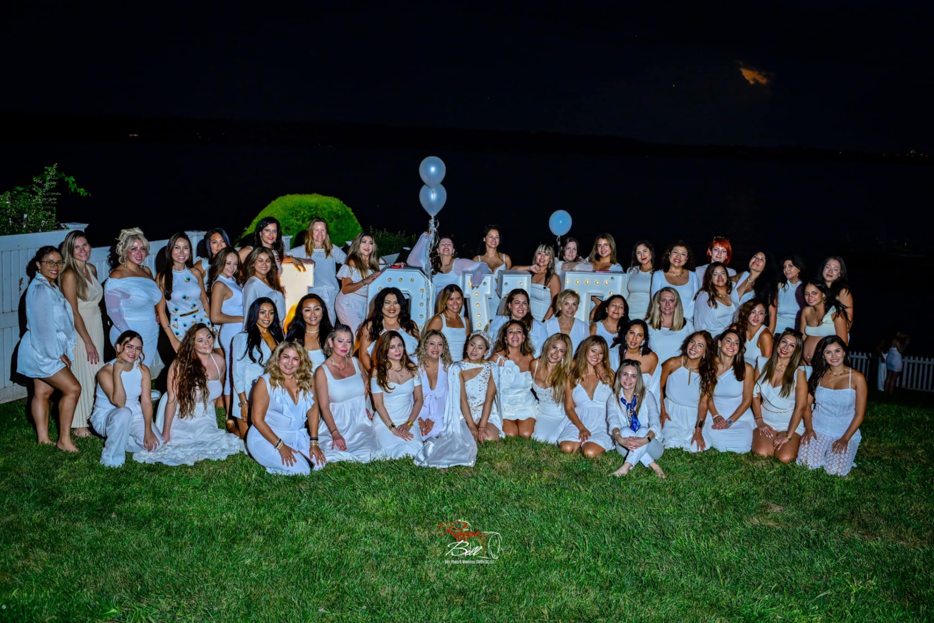 Evening group photo of the women in white with balloons